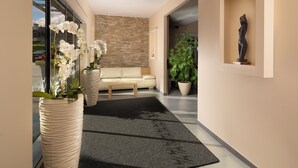 Un salon moderne avec un canapé beige, un tapis noir et une grande plante en pot.