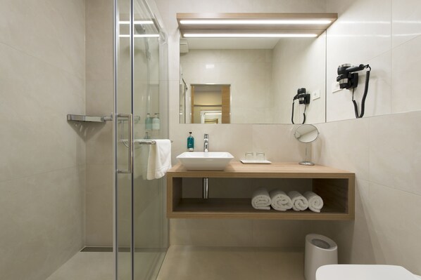 Une salle de bain moderne avec une douche à parois de verre, un lavabo avec un miroir et une étagère avec des serviettes.