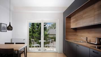 Una cocina moderna con armarios oscuros, encimera de madera y una puerta corrediza de vidrio que da a un patio exterior con sillas.