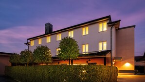Un hôtel moderne doté d’un toit plat, de nombreuses fenêtres et d’une haie bien entretenue à l’avant.