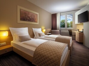 A hotel room with two beds, a desk, a chair, a TV, and a window with curtains. - Ahotel Hotel Ljubljana (Ljubljana)