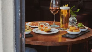 Een bar met een ronde tafel, een biertappatuur en een glas bier.