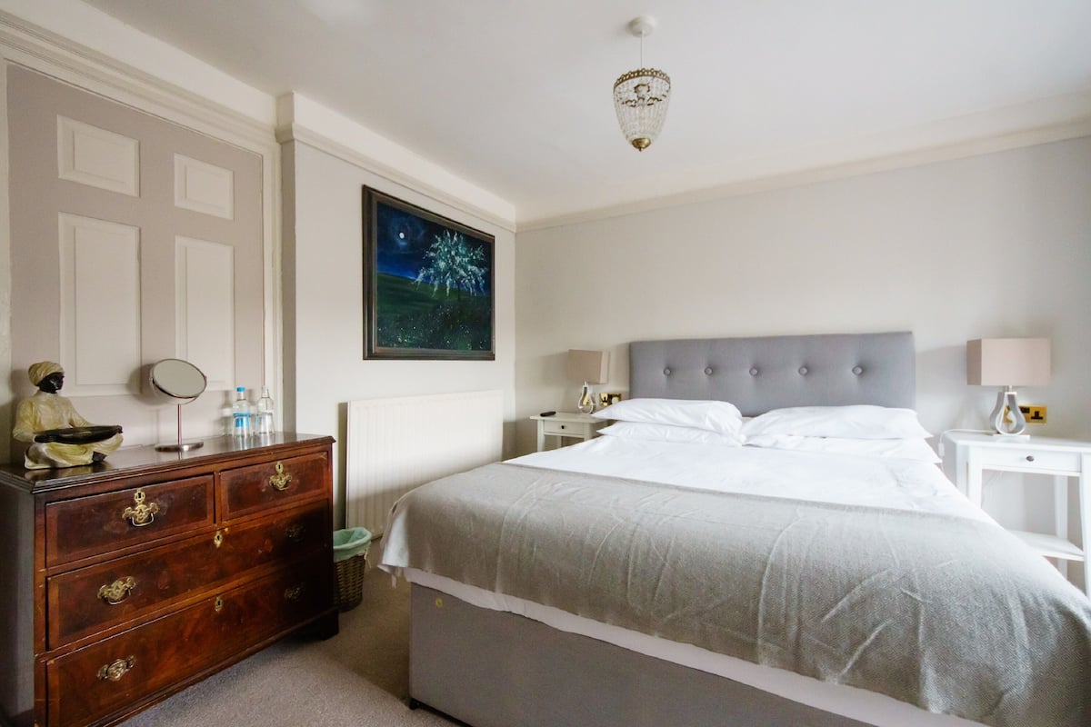 A bedroom with a bed, dresser, nightstands, and a chandelier.