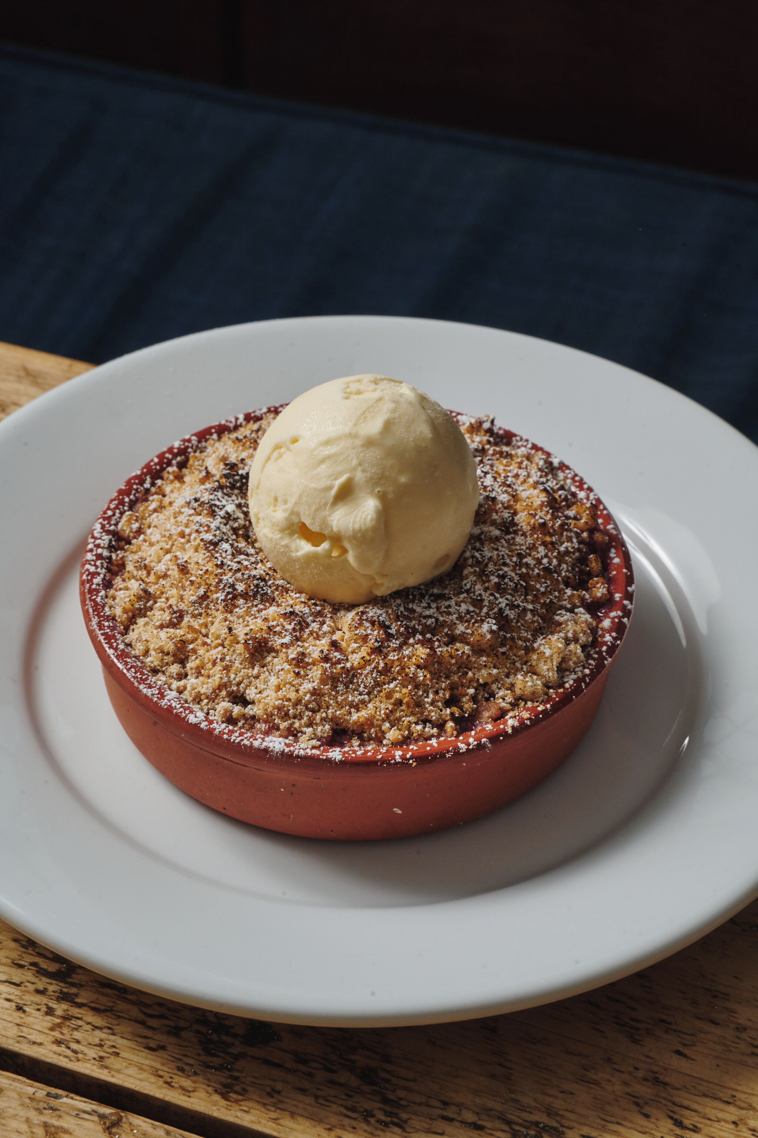 A dessert in a red ramekin on a white plate.