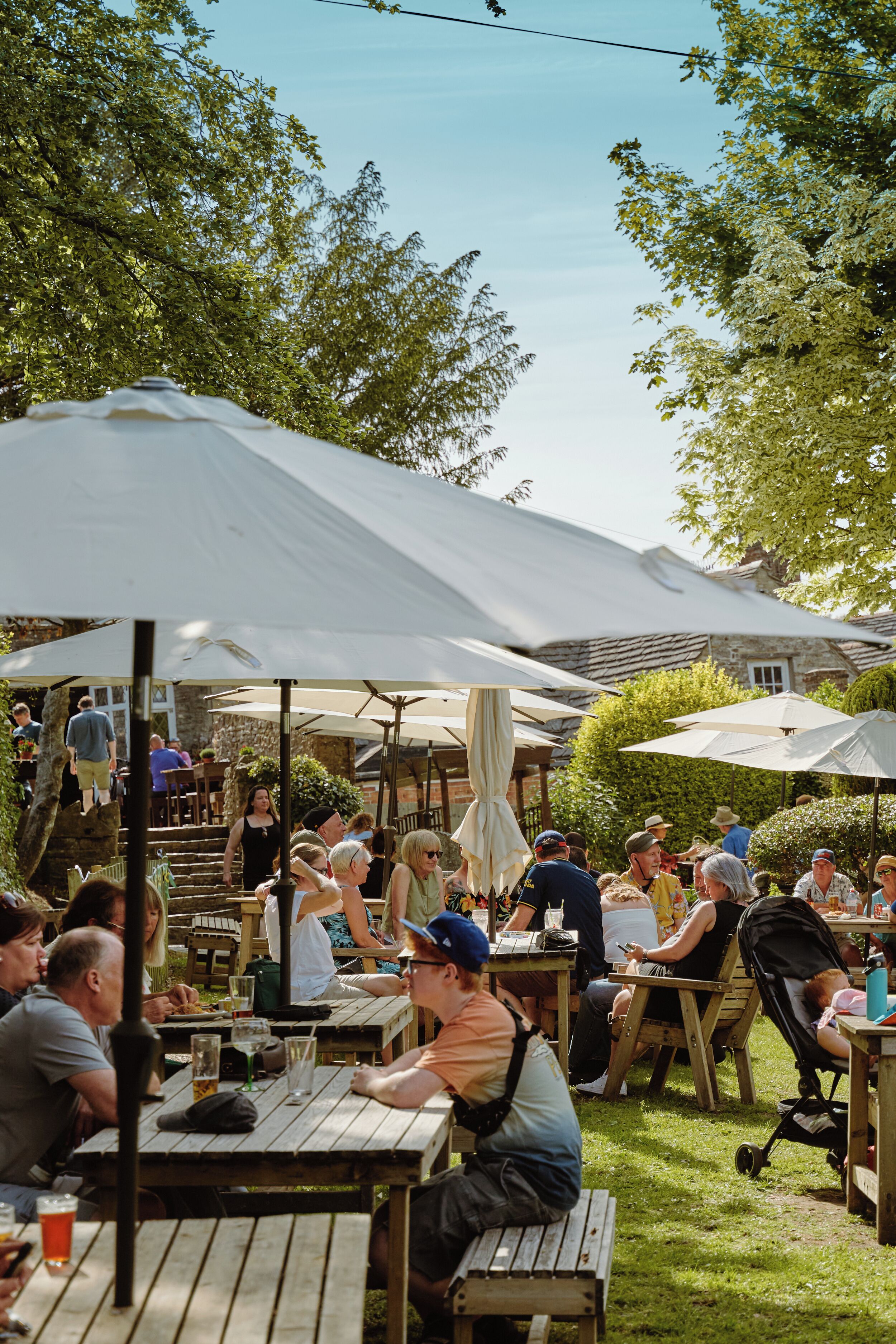 Een terras met houten tafels en witte parasols.