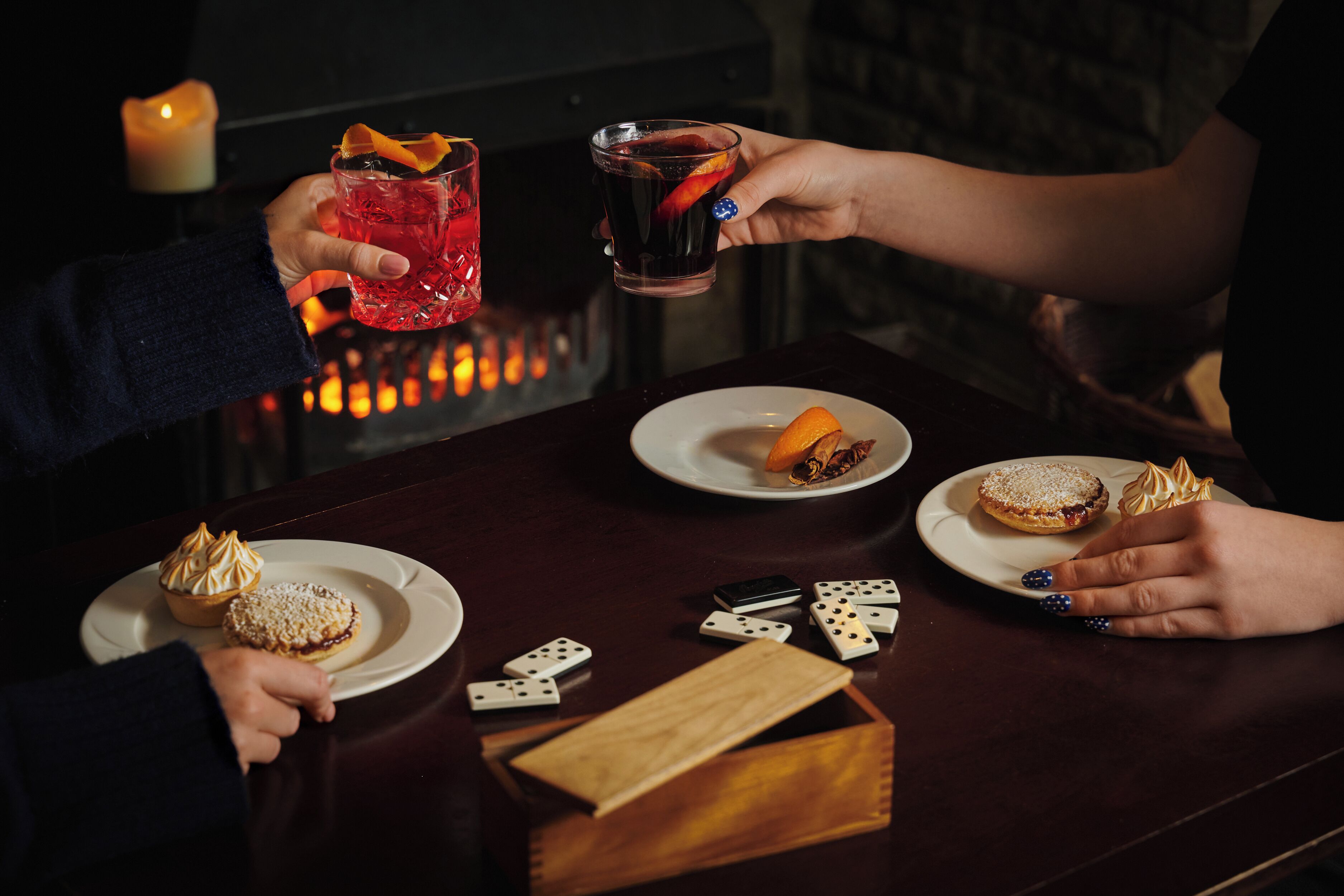 A table with two plates of desserts, a candle, and playing cards.