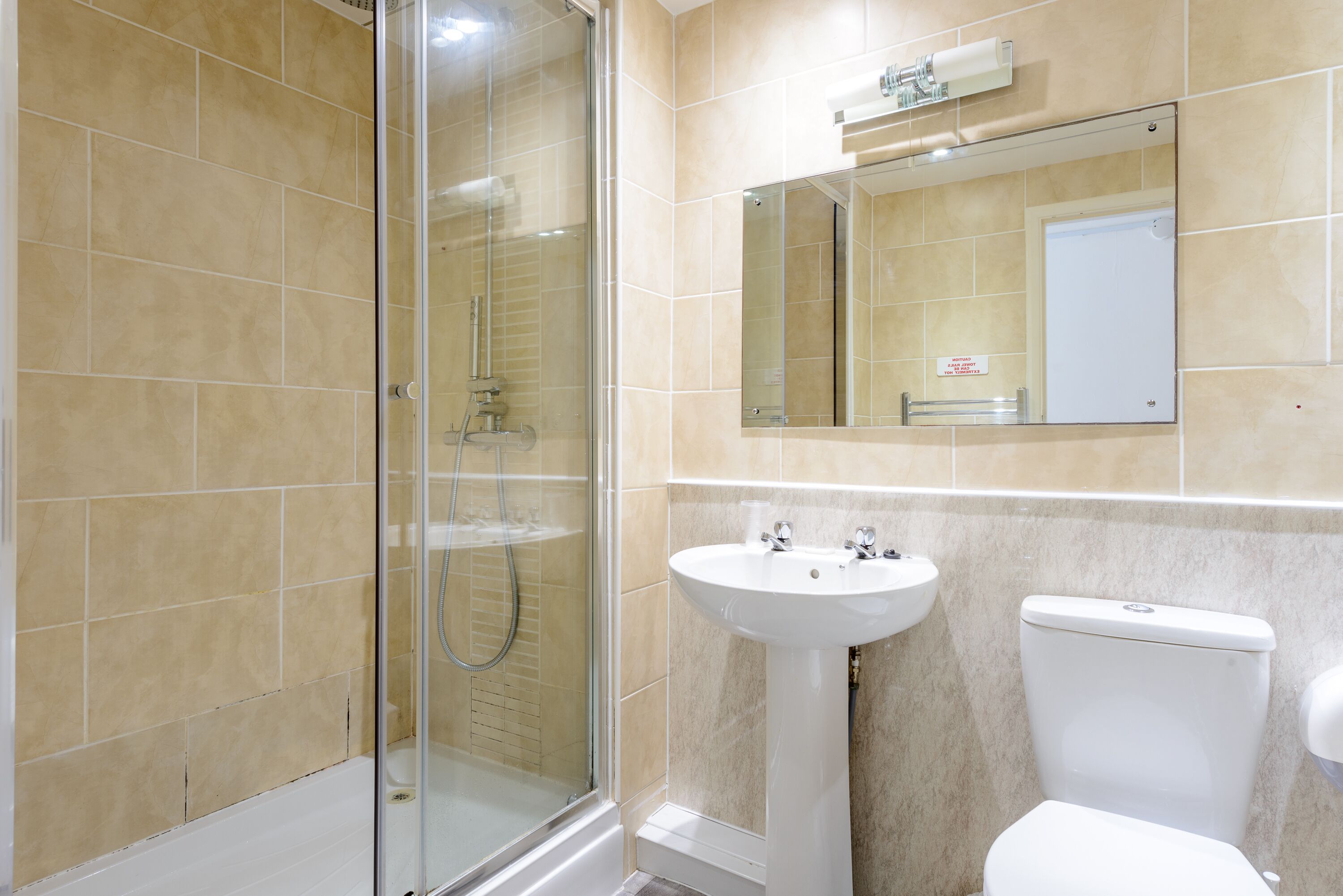 Un bany amb dutxa trencada per vidre, un lavabo i un vàter.