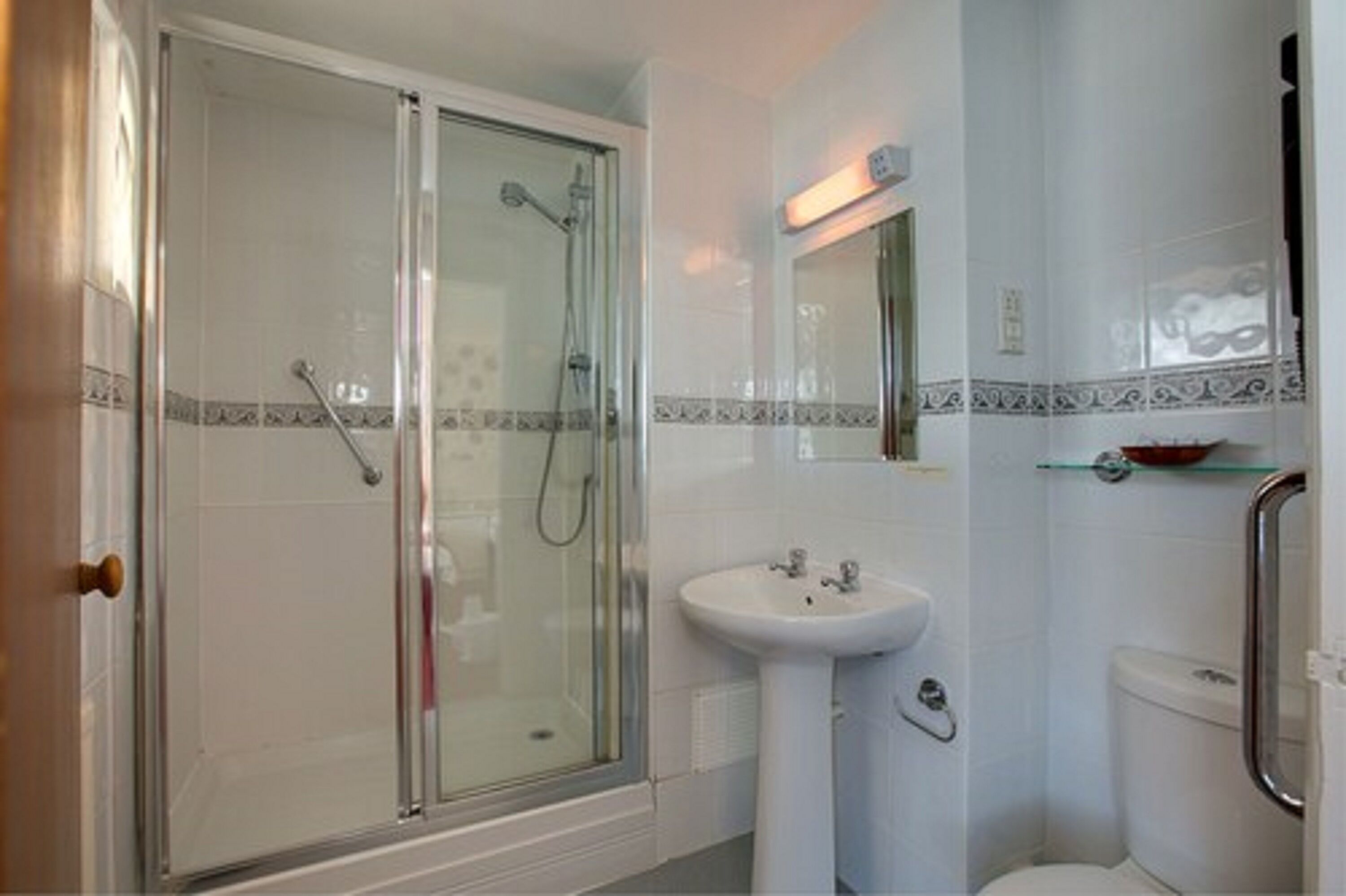 Ein Badezimmer mit Duschkabine, Waschtisch und Toilette.