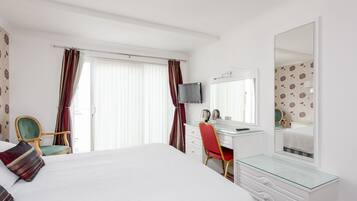 Une chambre d’hôtel comprenant un lit, un bureau, une chaise, une commode, un miroir et un téléviseur.