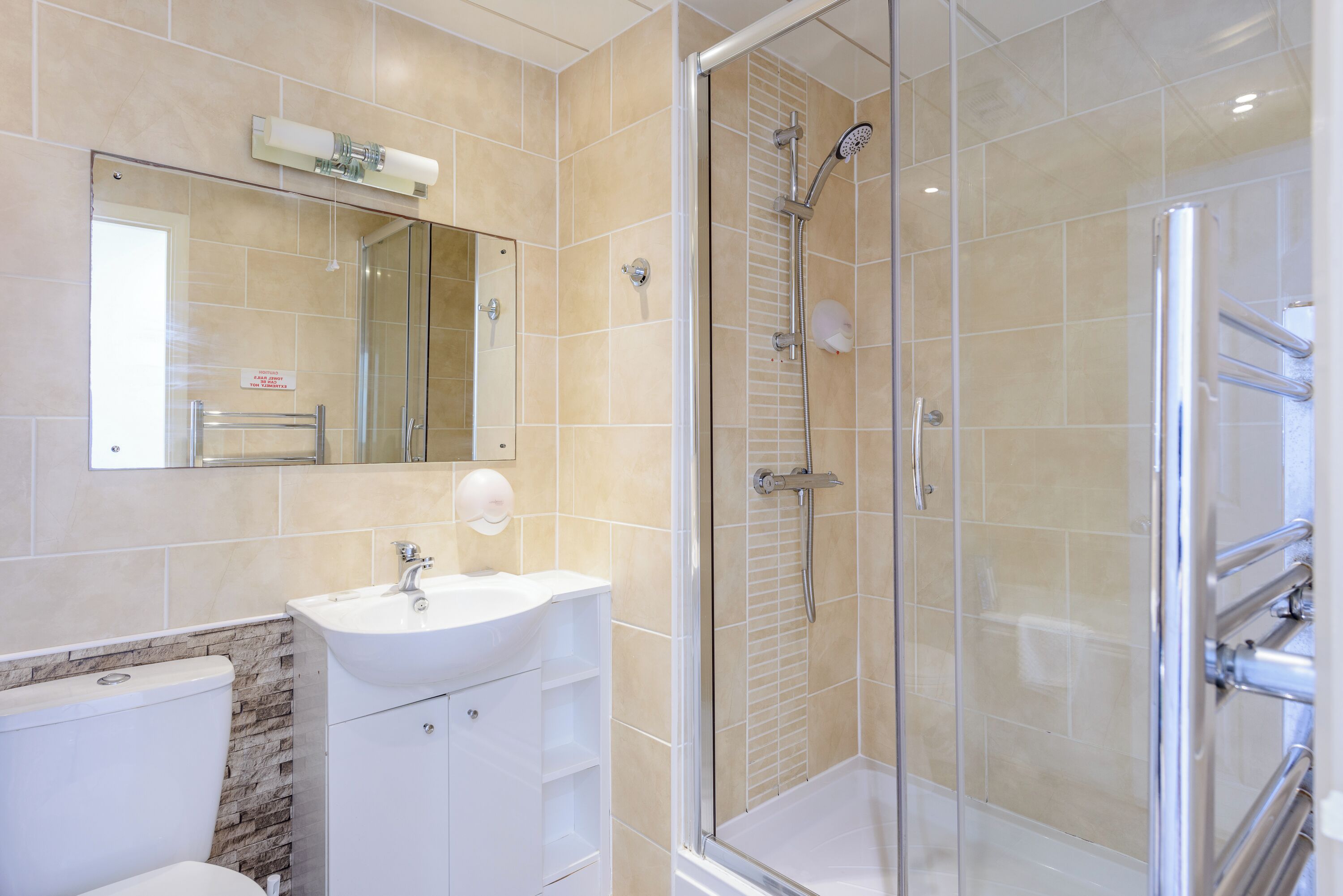 A bathroom with a glass-enclosed shower, a white sink, and a mirror above it.