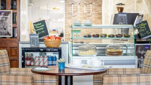 A coffee shop with a menu board, a display case with pastries, and seating area. - Barrowfield Hotel (Newquay)