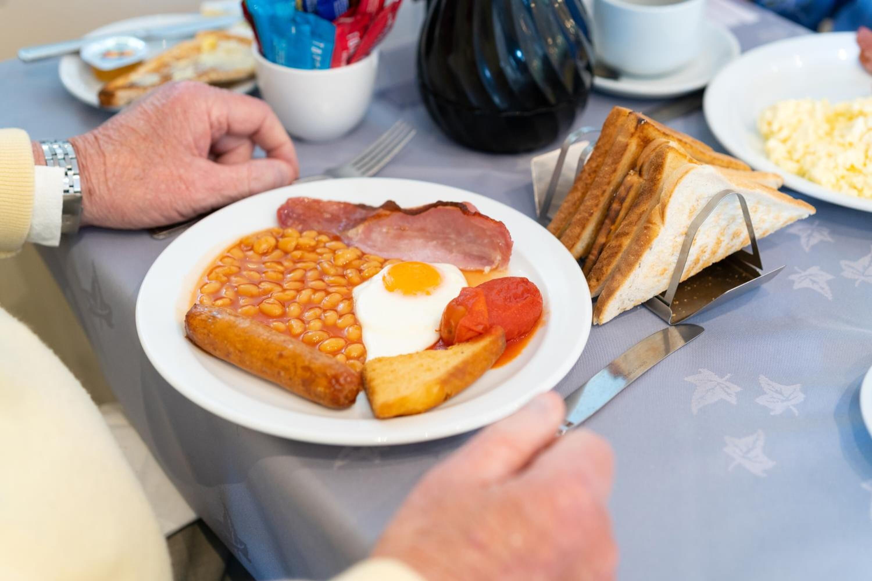 Un plato de comida para el desayuno con frijoles, huevos, tocino y tostadas.