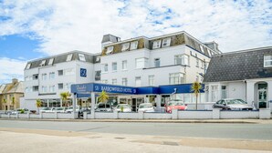 Un hôtel à plusieurs étages, doté d’une façade bleue et blanche, de nombreuses fenêtres et d’un espace de stationnement à l’avant.