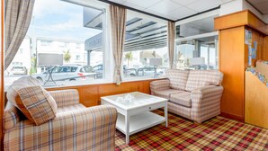 A room with a plaid sofa, a white coffee table, and a view of the street outside. - Barrowfield Hotel (Newquay)
