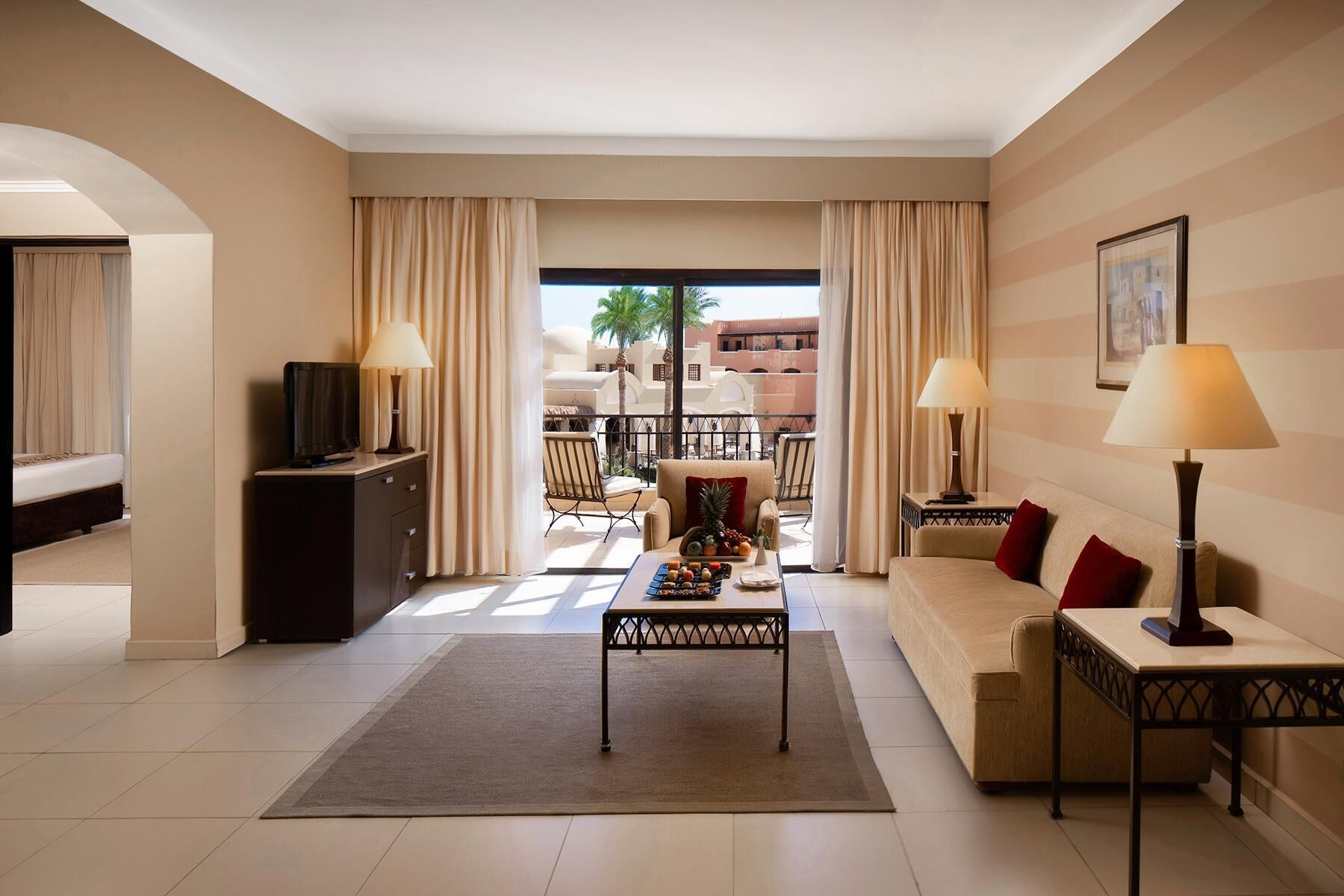 Une chambre d’hôtel avec un canapé, une table basse, une télévision et un balcon doté de mobilier d’extérieur.