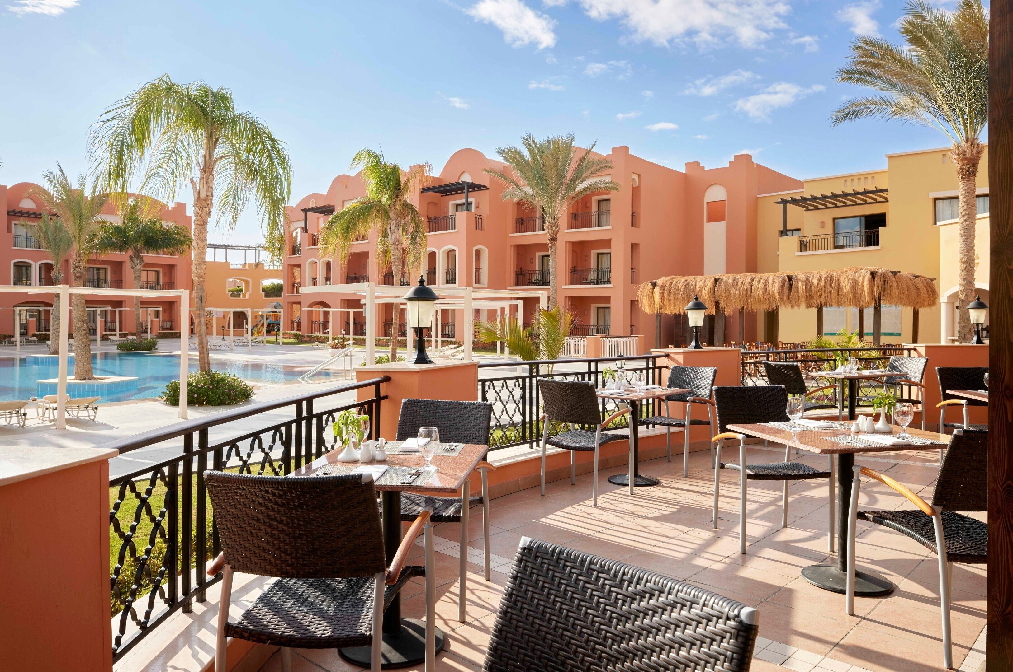 A hotel patio with outdoor seating, a pool, and a view of the building's architecture.