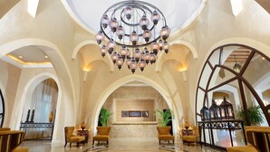A lobby with a grand chandelier, arched ceilings, and a marble floor.