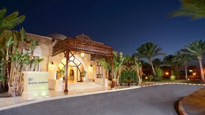 A hotel entrance with a covered walkway, palm trees, and a sign reading "Jaz DAREL MADINA".