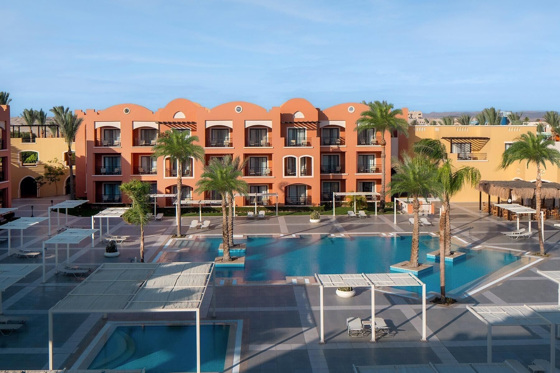 Un hôtel doté de nombreux balcons, d’un espace piscine et de palmiers.