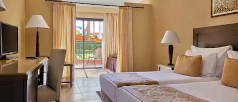 A hotel room with two beds, a desk, a chair, and a TV.