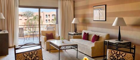 A hotel room with a balcony, a sofa, a coffee table, and a dining table.