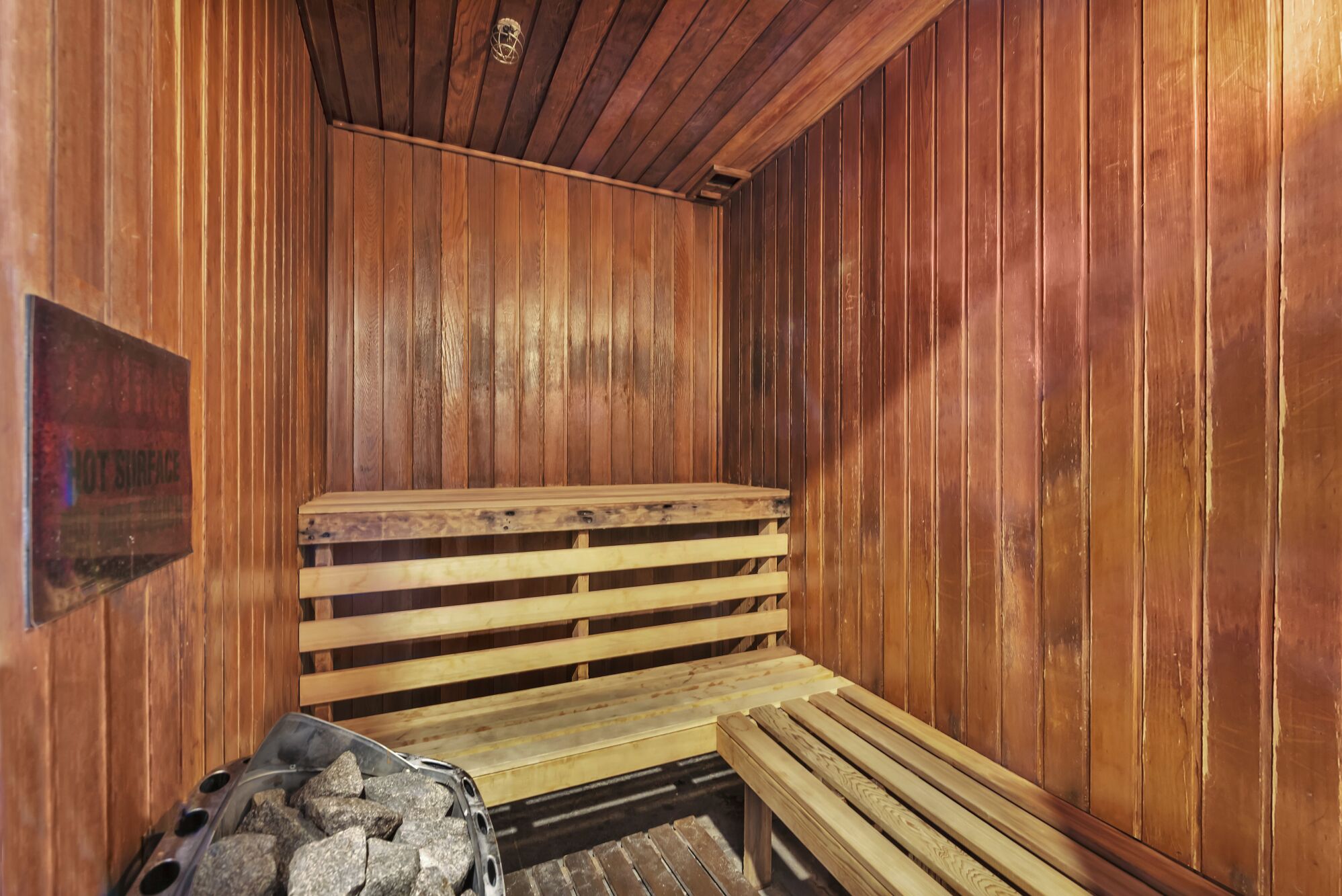 Sauna, jossa on puiset lauteet ja kiviuuni.