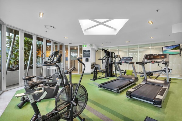 A gym with treadmills, elliptical machines, and a fan.