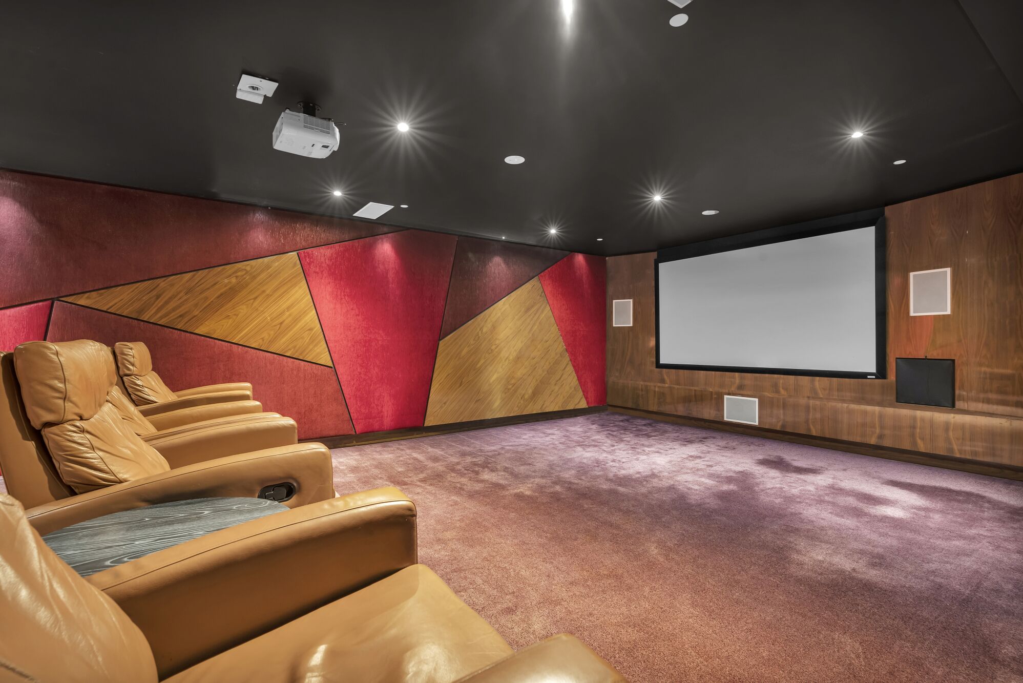 Un cine con butacas reclinables de cuero, una pantalla grande y un diseño de pared de madera.
