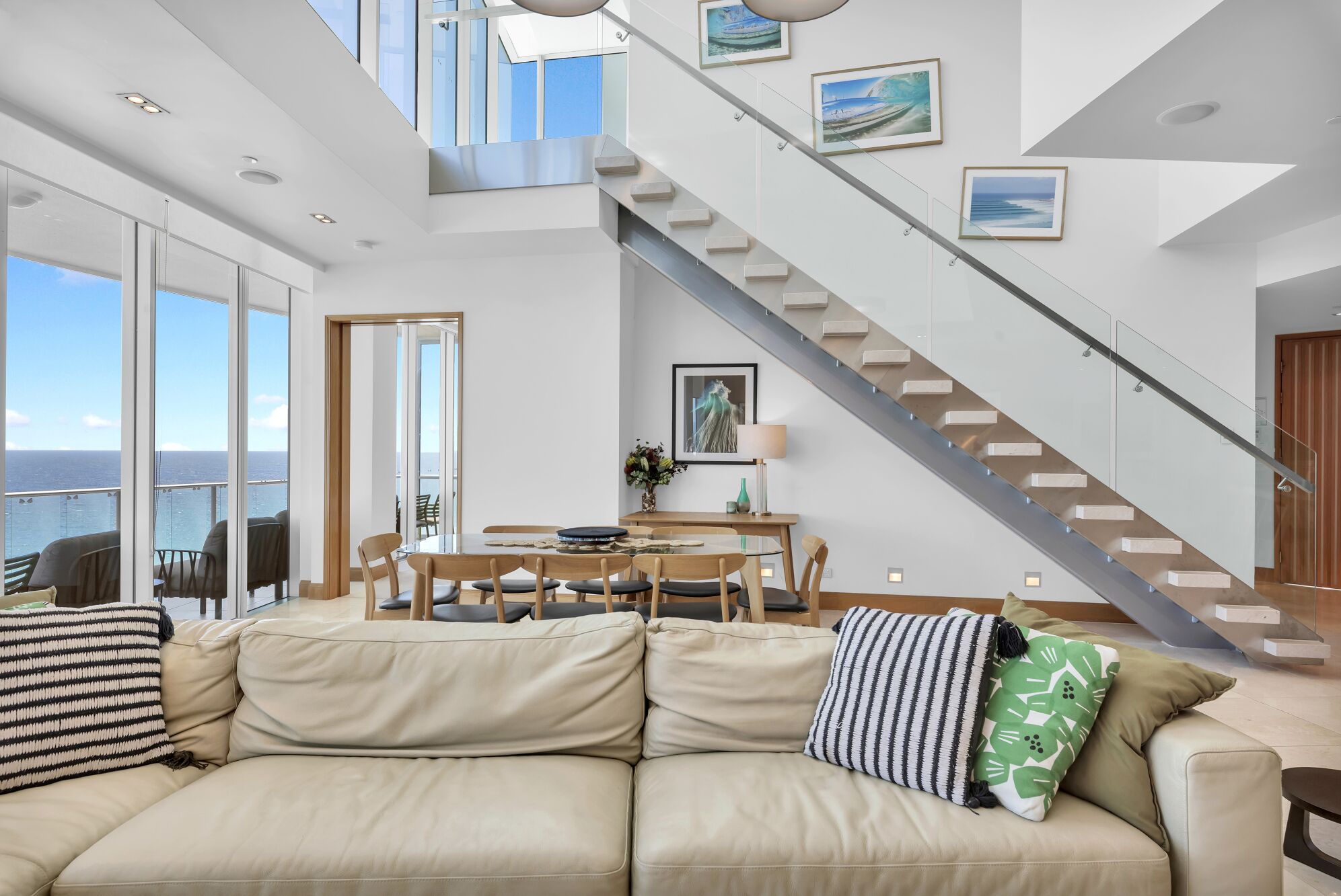 A modern interior with a sofa, dining table, and staircase.