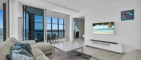 A modern living room with a large window, a flat-screen TV, and a sofa.