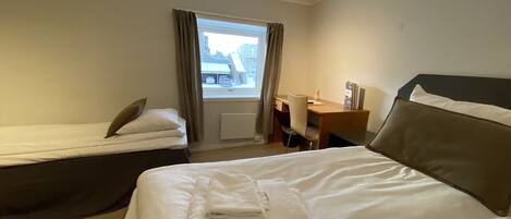 Een hotelkamer met een groot bed, een kleiner bed, een bureau en een stoel.