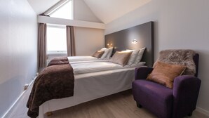Une chambre à coucher avec un lit, deux tables de chevet, une chaise et une fenêtre.