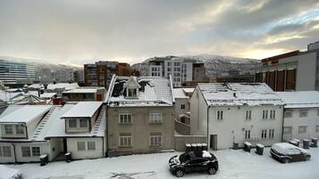 Un área urbana nevada con edificios y coches aparcados.