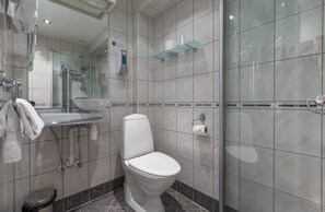 Enjoy a clean and contemporary bathroom with a sleek toilet, glass shower enclosure, and convenient hand sanitizer dispenser.
