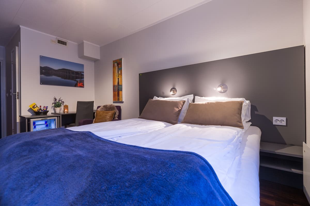 Une chambre d’hôtel moderne dotée d’un grand lit, d’un bureau avec un ordinateur et d’un téléviseur fixé au mur.