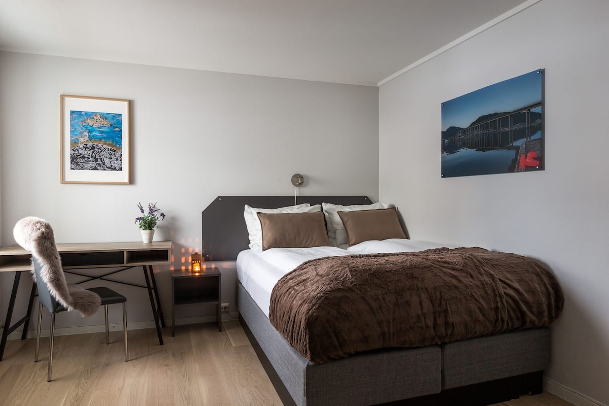 Une chambre  à coucher comprenant un lit, un bureau, une chaise et deux œuvres d’art accrochées au mur.