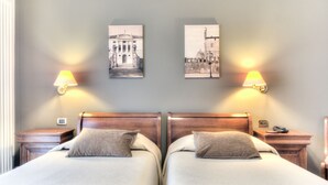A double room with two beds, each with a pillow and a nightstand. There are two wall-mounted lamps on either side of the beds. - Hotel Belvedere (Thiene)