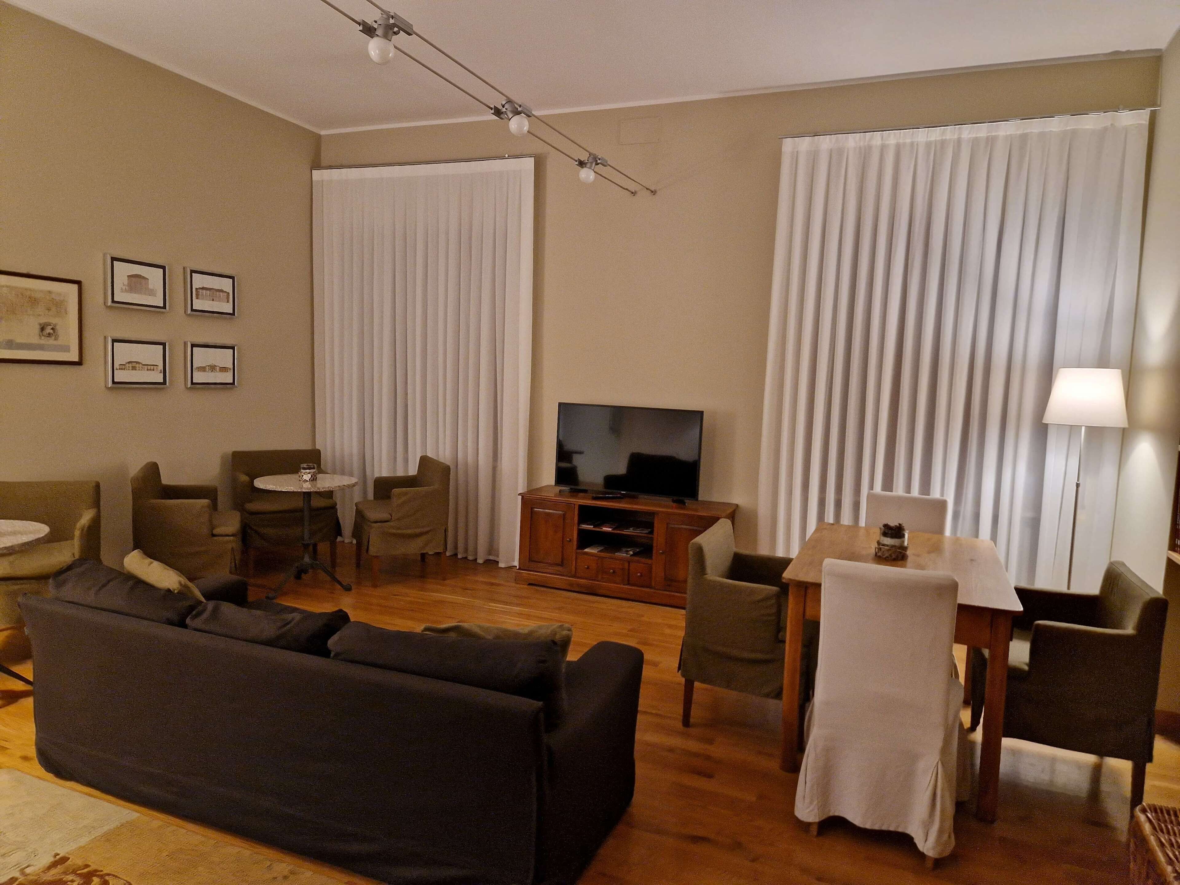 Una sala de estar con sofá, sillas, televisor y una mesa de comedor.
