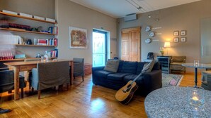 A cozy living room with a wooden dining table, a sofa, a guitar, and a coffee table. - Hotel Belvedere (Thiene)