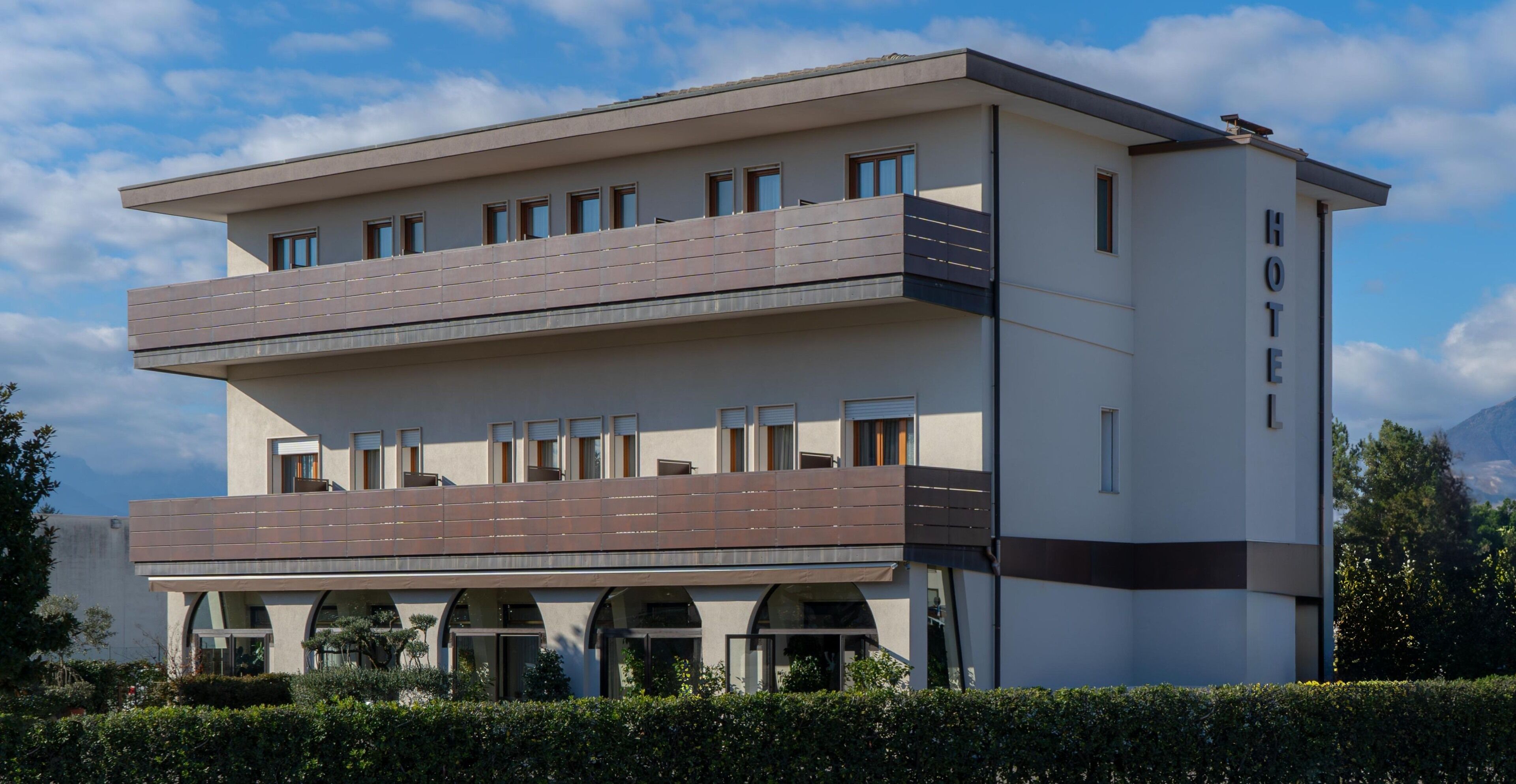 Een modern hotel met een tweelaags gebouw, balkons en een opvallend 'HOTEL'-bord aan de zijkant.