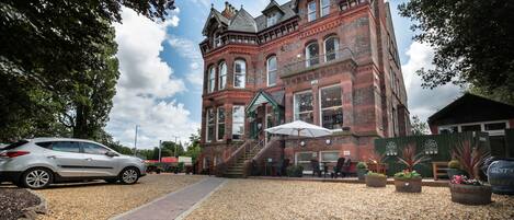 A historic building with a brick facade, large windows, and a covered outdoor seating area with umbrellas.