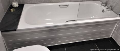 A modern bathroom with a large bathtub, a shower, and a toilet.