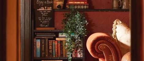 A cozy reading nook with a bookshelf, a mirror, and a lamp.