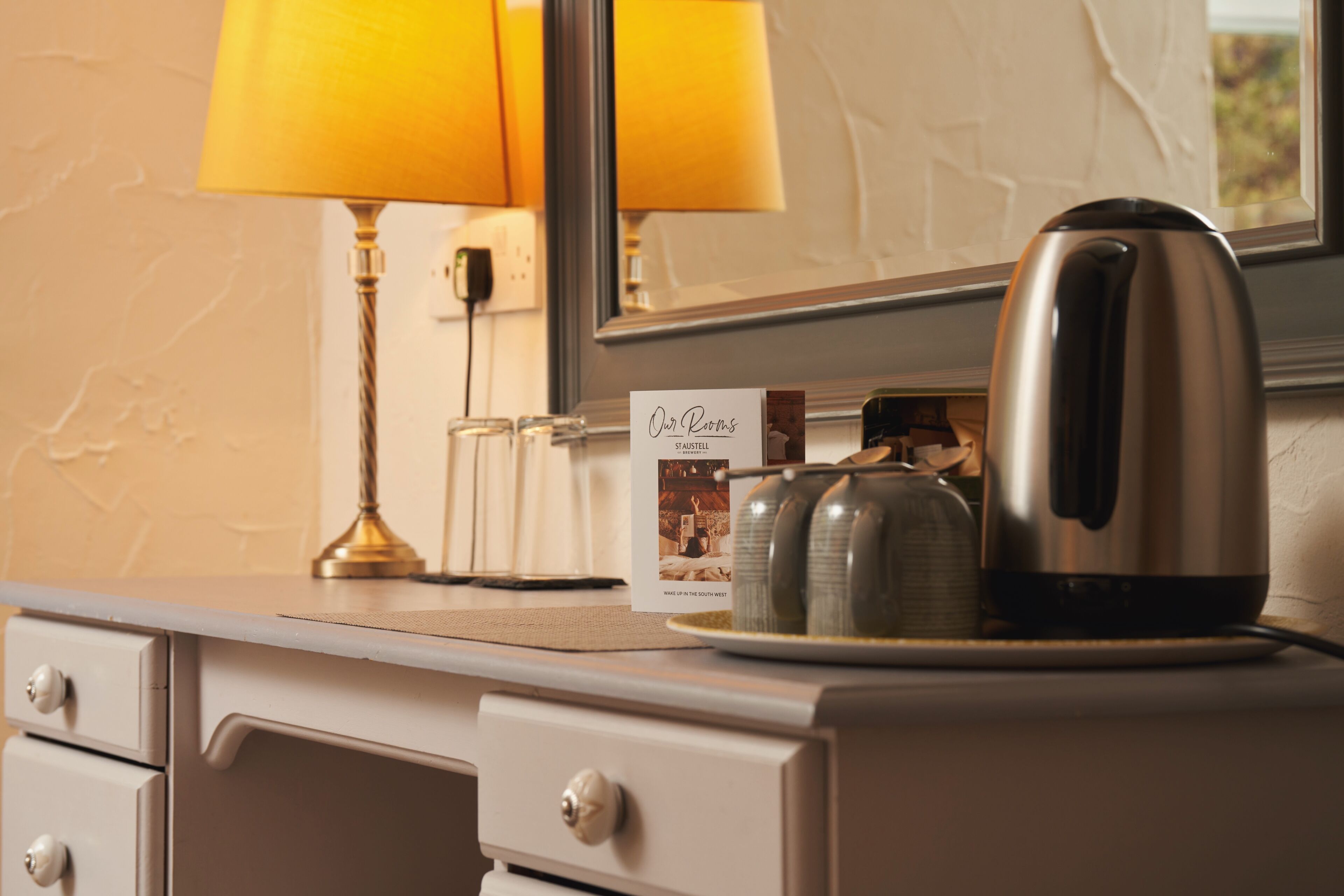 A hotel room with a minibar, a kettle, and a lamp.