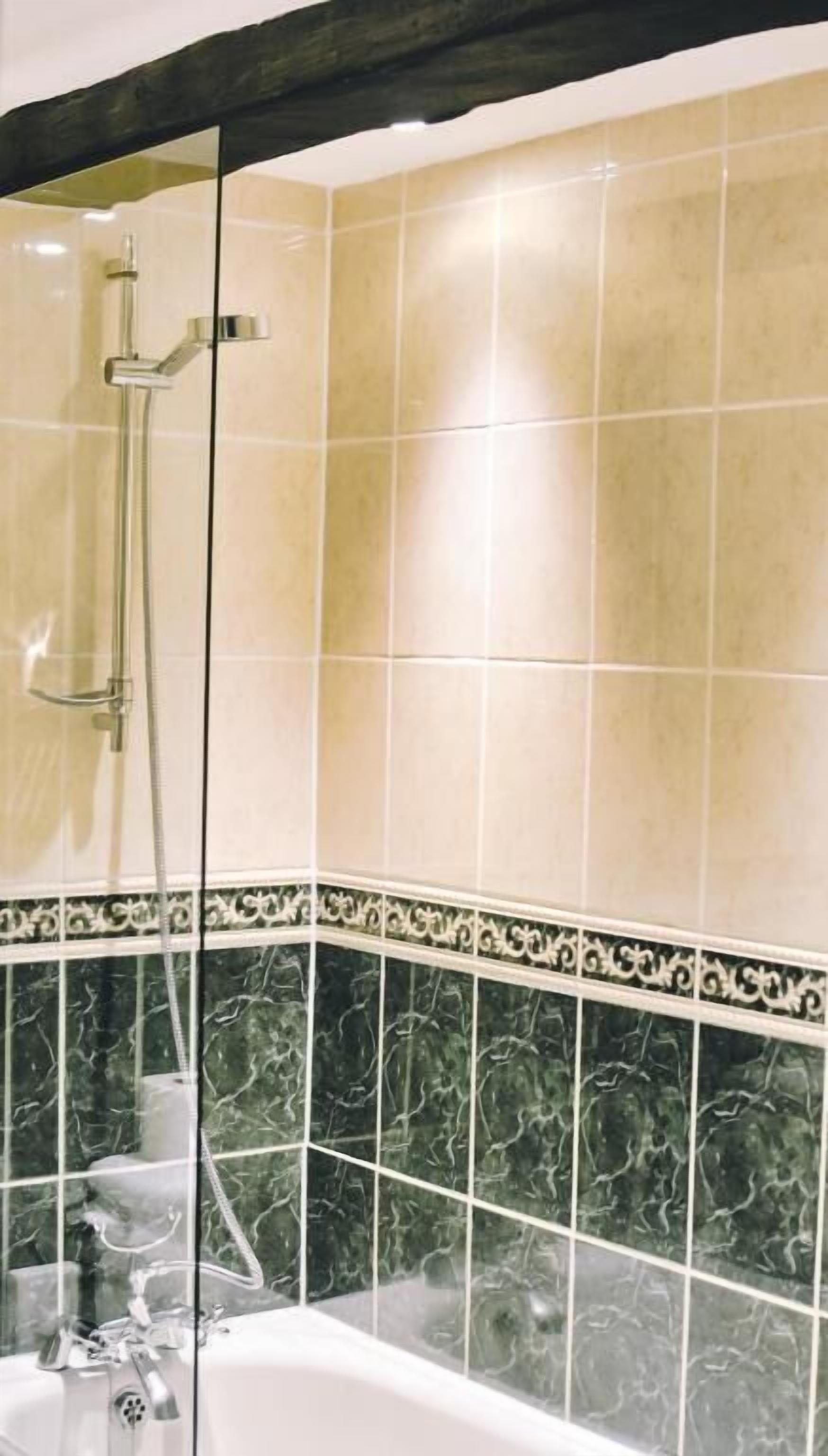 Casa de banho com chuveiro, banheira e paredes revestidas a azulejos.