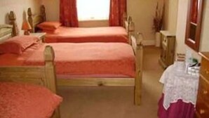 A room with two wooden beds, a small table, and a mirror. - Boars Head Hotel (Middlewich)