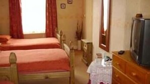 A room with two single beds, a dresser, a television, and a window with curtains. - Boars Head Hotel (Middlewich)