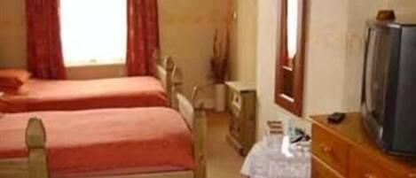 Quarto com duas camas de solteiro, cômoda, televisão e janela com cortinas.