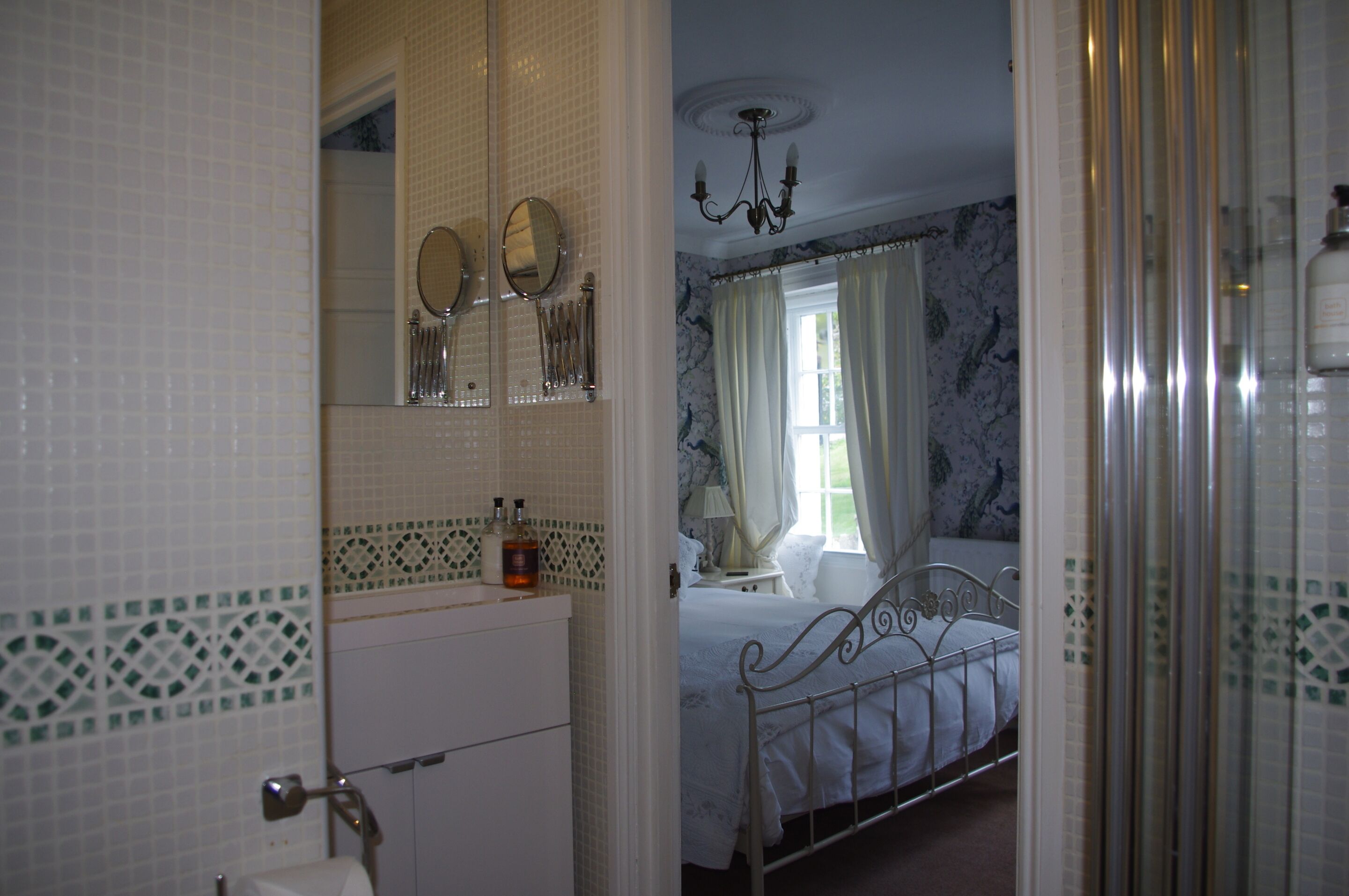 Quarto com cama, mesa de cabeceira, espelho e lustre.