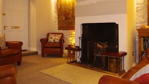 A cozy living room with a fireplace, leather armchairs, a rug, and a bookshelf. - Brunswick House (Barnard Castle)
